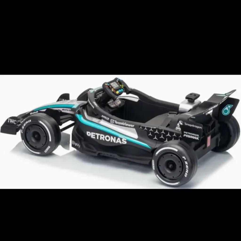 Coche eléctrico infantil estilo F1 Mercedes-AMG Petronas 12V en negro con detalles turquesa y plateados, alerón trasero, volante con botones y llantas