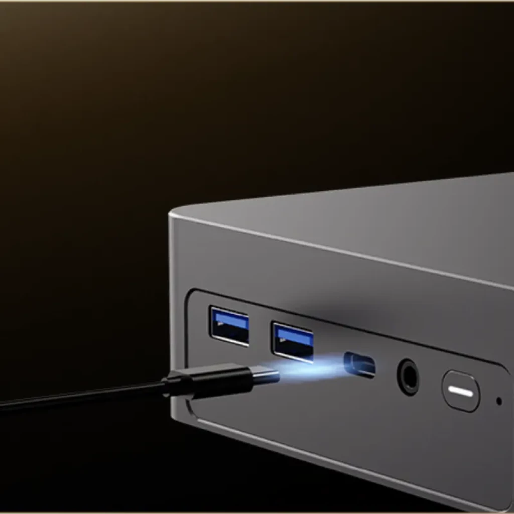 Mini PC gris con frontal que muestra puertos USB 3.0 azules, USB-C iluminado, jack de audio y botón de encendido
