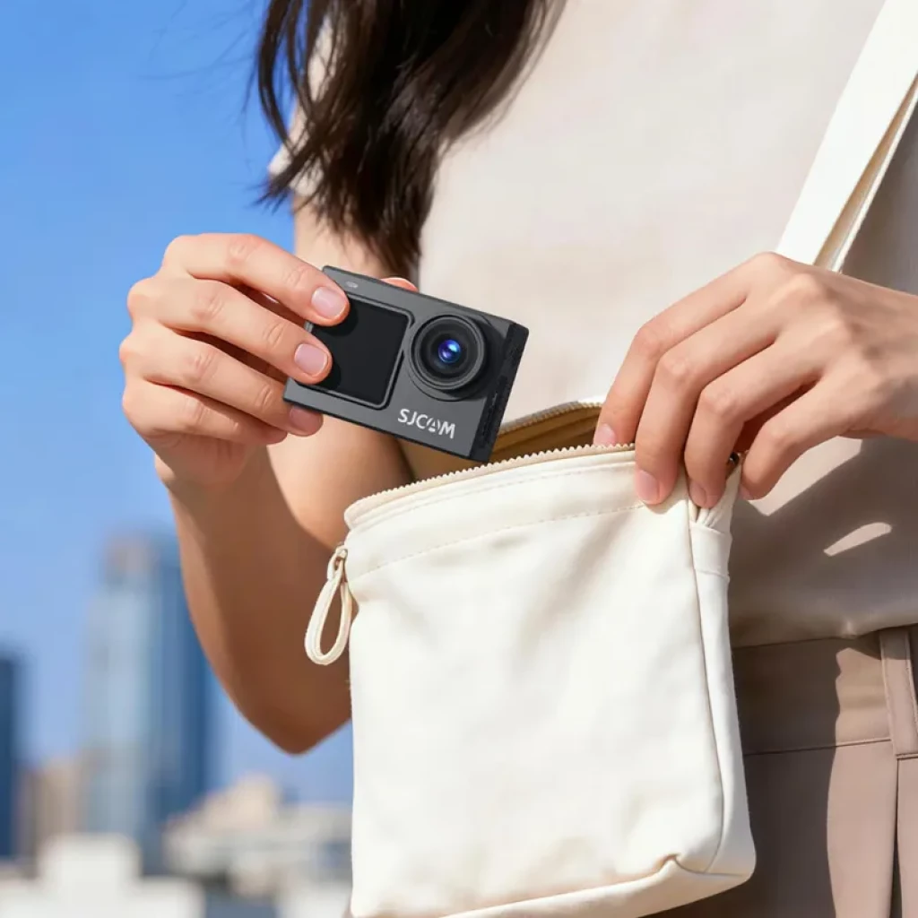 Caméra d action SJCAM SJ6 Ultra compacte noire, double écran avant et arrière, grand objectif, tenue en main et glissée dans une petite pochette blanche