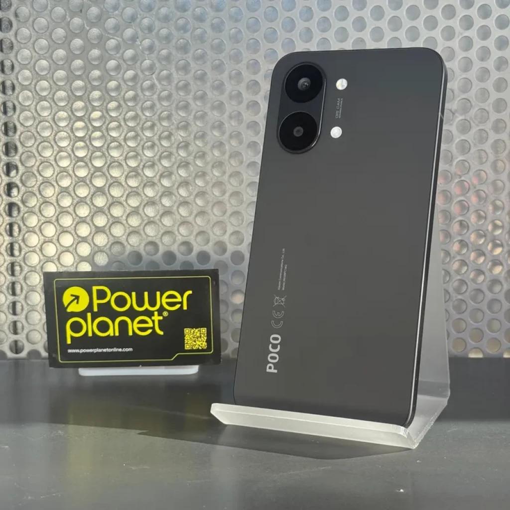 Smartphone preto com traseira fosca, dois câmeras grandes no canto, logotipo POCO vertical e corpo fino apoiado em suporte acrílico transparente