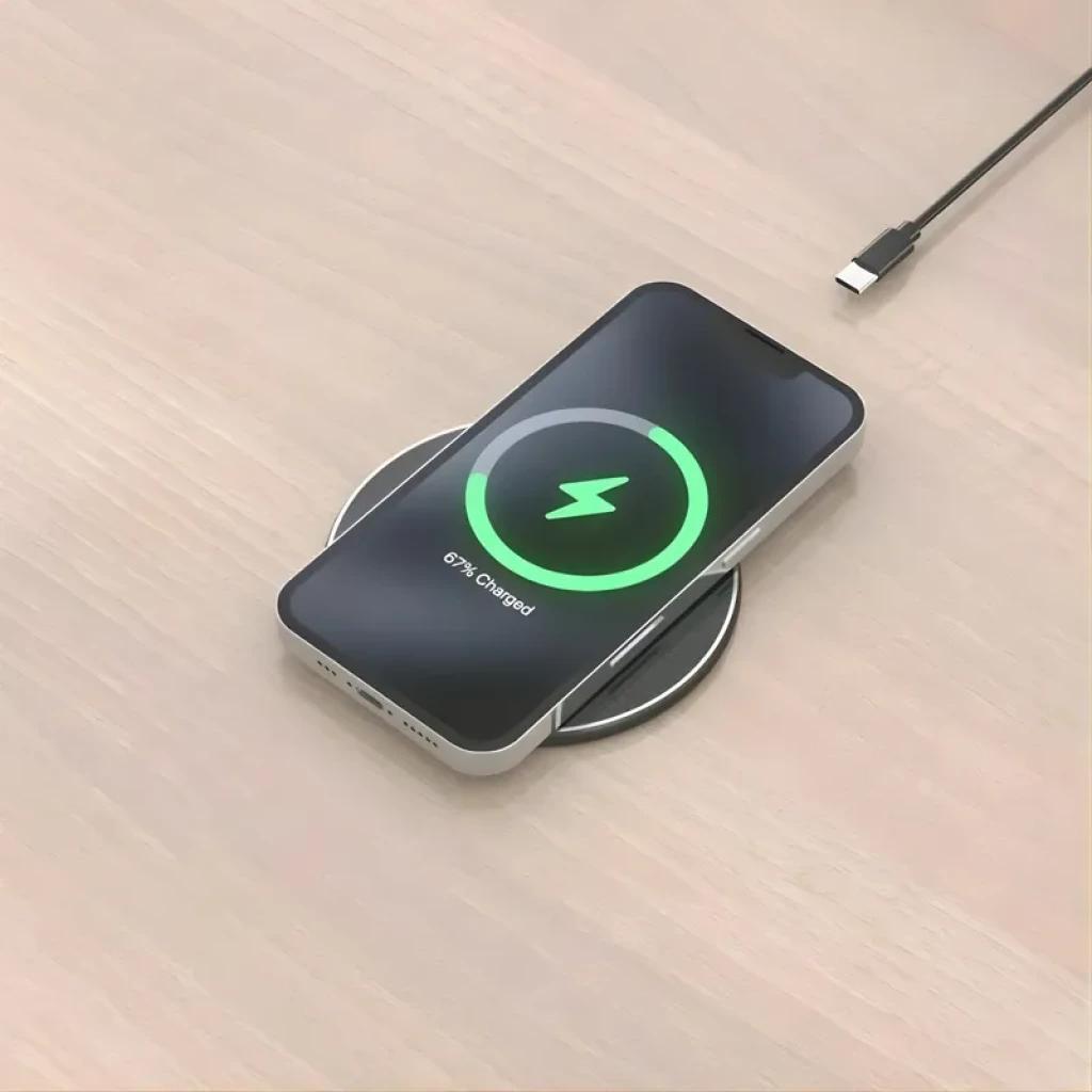 Aisens ASCH-15W1WC058-W Carregador sem fios Qi 15 W com USB-C, base preta circular e fina; smartphone sobre a base mostrando carregamento ativo