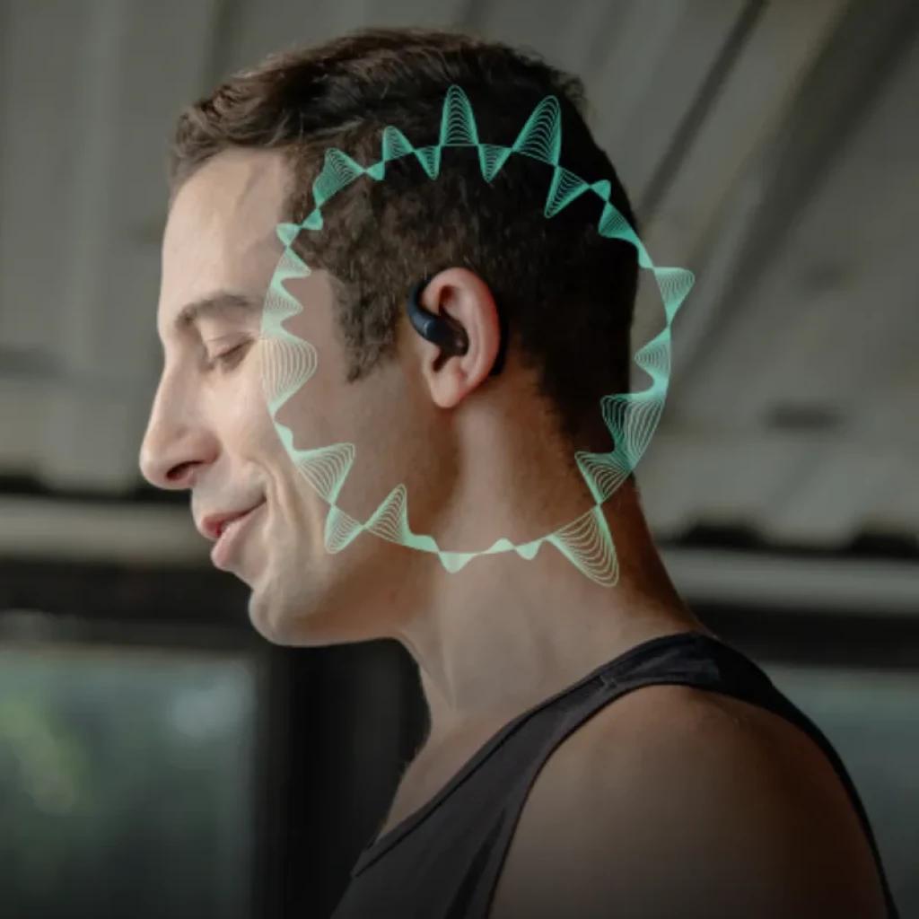 Hombre usando auricular open ear TicNote Pods 4G en color negro; diseño discreto detrás de la oreja con onda sonora verde indicando transcripción IA y eSIM