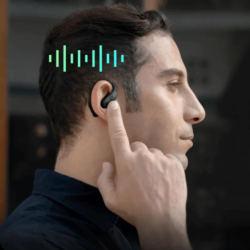 Auricular open-ear TicNote Pods 4G en oreja, diseño negro con micrófono integrado, control táctil y ondas que representan transcripción IA y conectividad