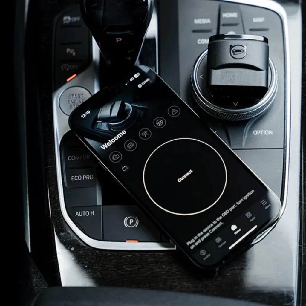 Escáner de diagnóstico OBDeleven 2 Pro Pack para VAG con Bluetooth BLE, app móvil mostrando pantalla de conexión sobre consola central de automóvil premium