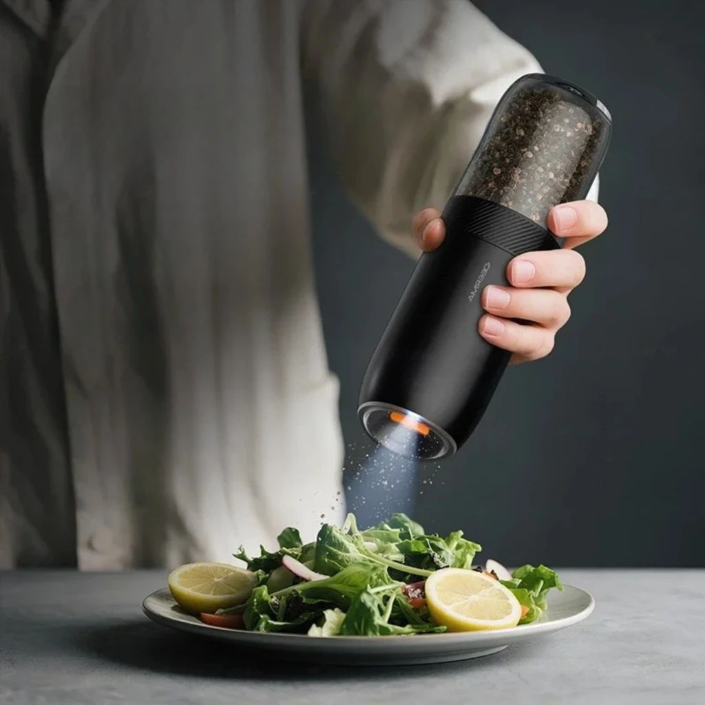 Deerma Electric Salt Extractor YM01, molinillo eléctrico negro con cuerpo transparente y sensor de gravedad; luz LED y molienda directa sobre platos
