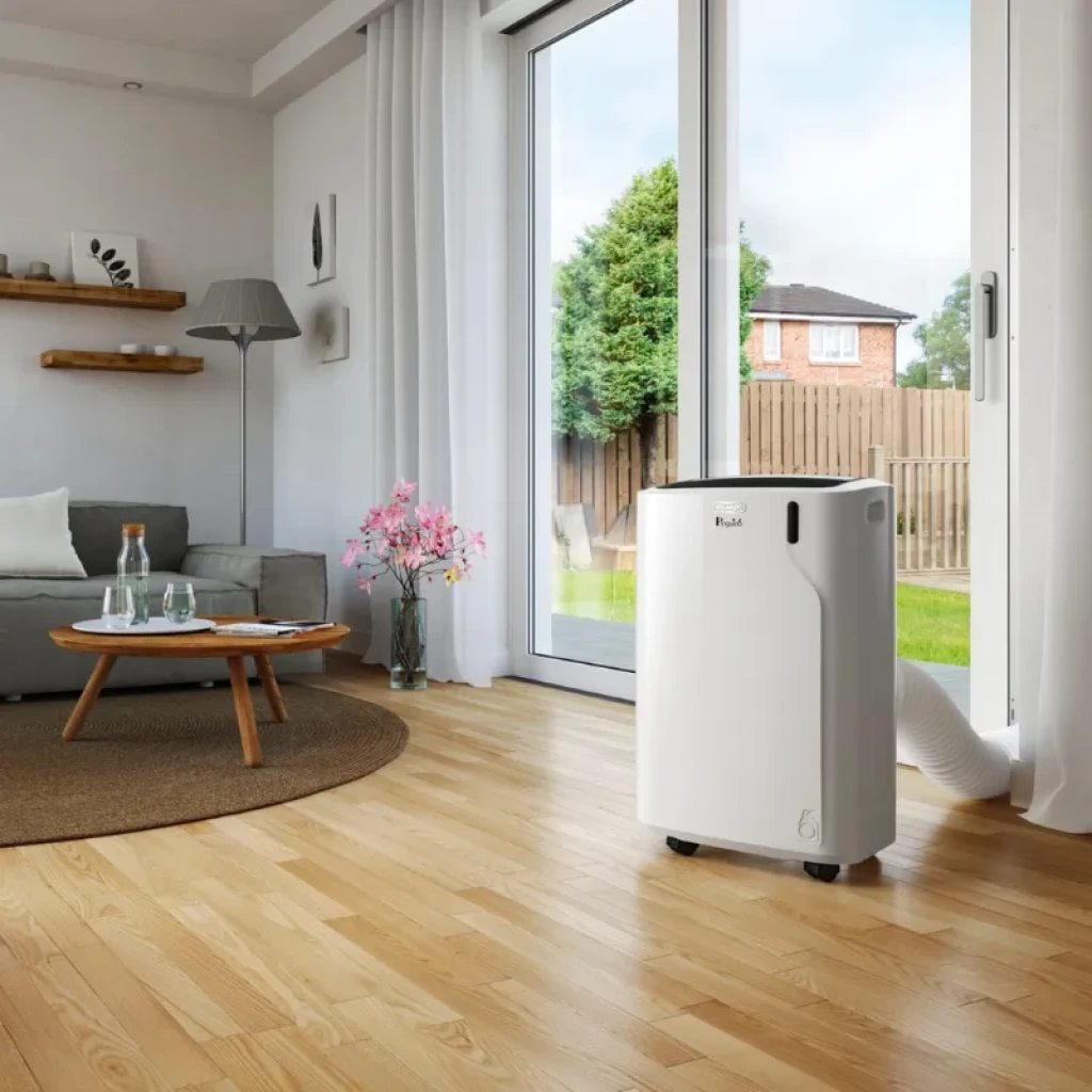 De'Longhi PAC EM90K Silent aire acondicionado portátil blanco con ruedas, panel superior con controles, manguera de ventilación a ventana en sala moderna