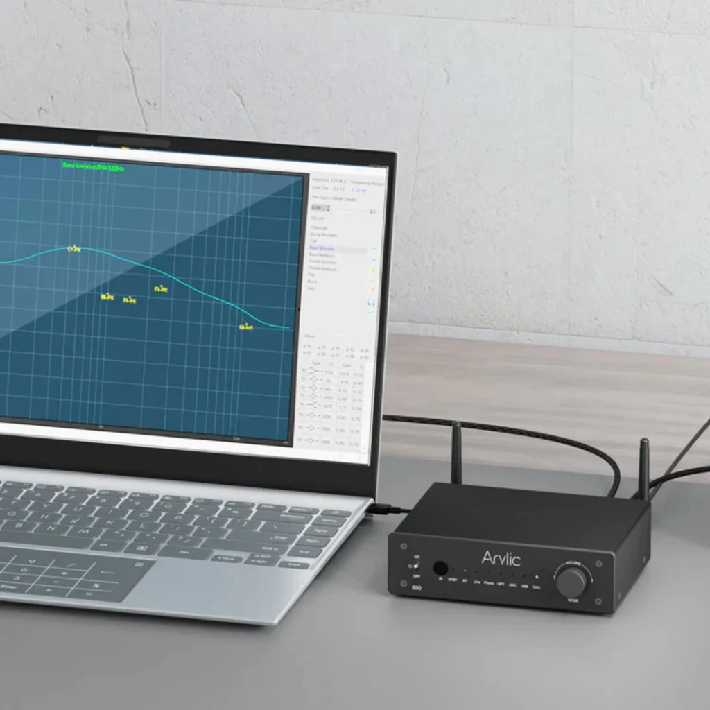 Arylic B50 Amplificador Bluetooth 5.2 Negro compacto, caja metálica mate, perilla de volumen, leds frontales y dos antenas traseras junto a laptop conectada