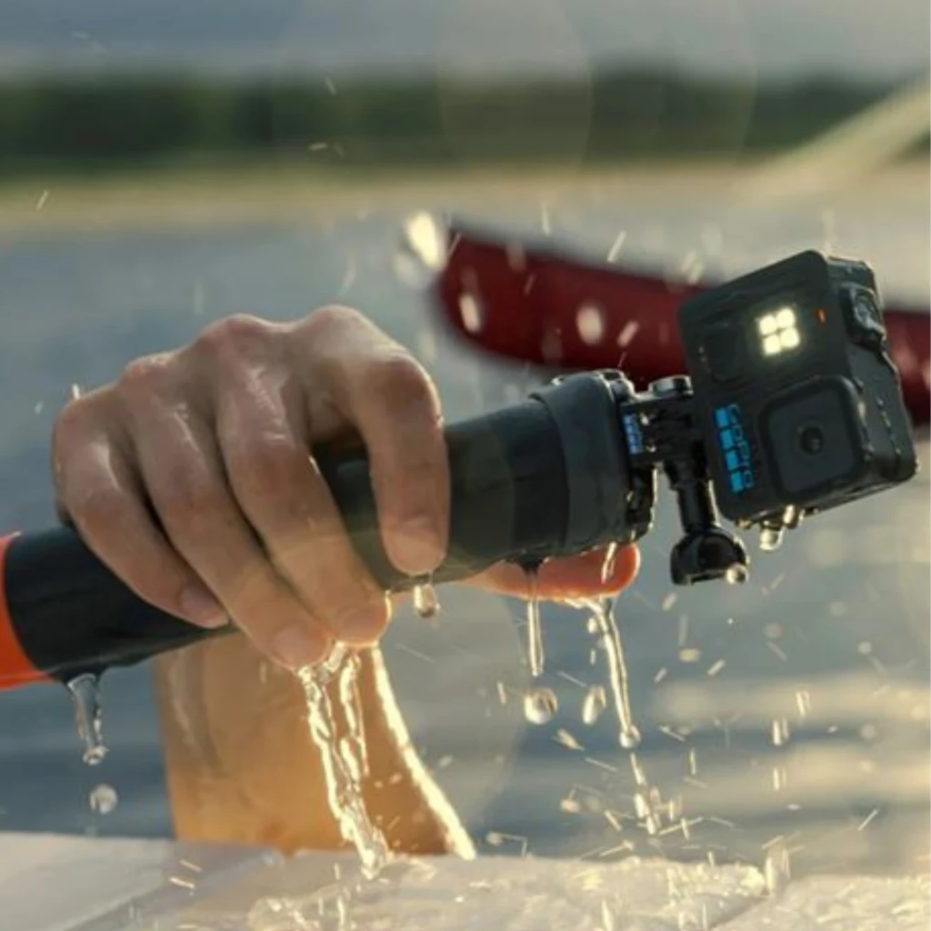GoPro Lit Hero 4K 60fps 12 MP, sumergible 5 m con HyperSmooth, montada en tubo de agarre; carcasa negra, LEDs frontales encendidos y gotas de agua en acción
