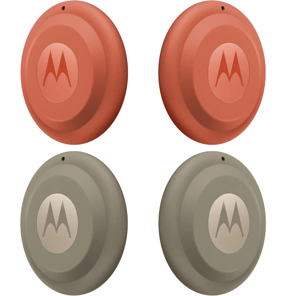 Moto Tag 2.0 Motorola en cuatro rastreadores circulares, dos en rojo terracota y dos en gris oliva, con logotipo M central y diseño de anillos concéntricos