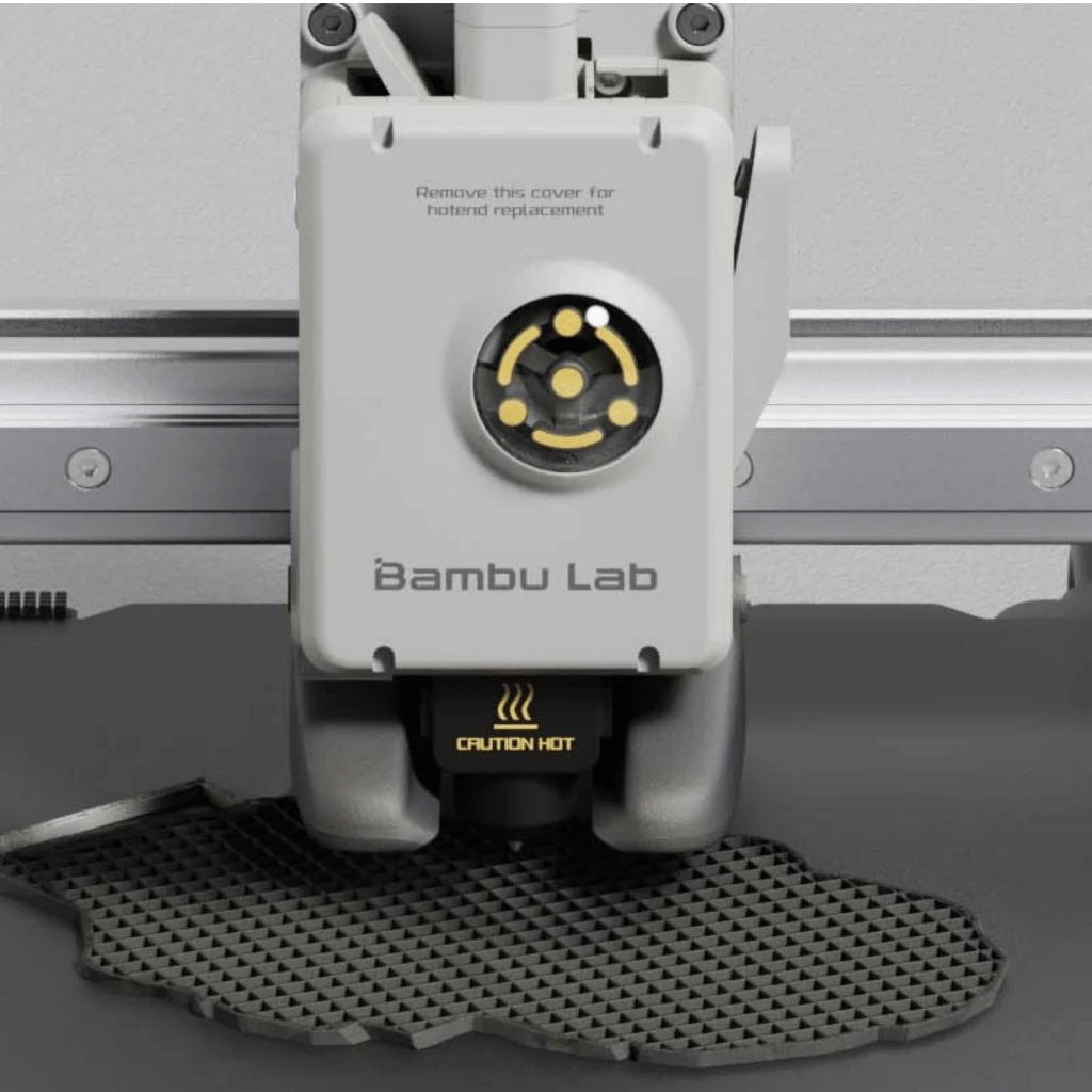 Cabezal de impresión Bambu Lab A1 Mini con boquilla y advertencia Caution Hot, imprimiendo patrón de rejilla en cama, carcasas grises y detalles dorados