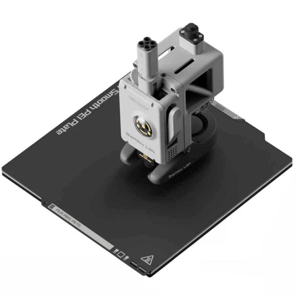 Módulo extrusor Bambu Lab A1 Mini gris con ventiladores y hotend, montado sobre base Smooth PEI Plate negra desmontable, diseño compacto y preciso