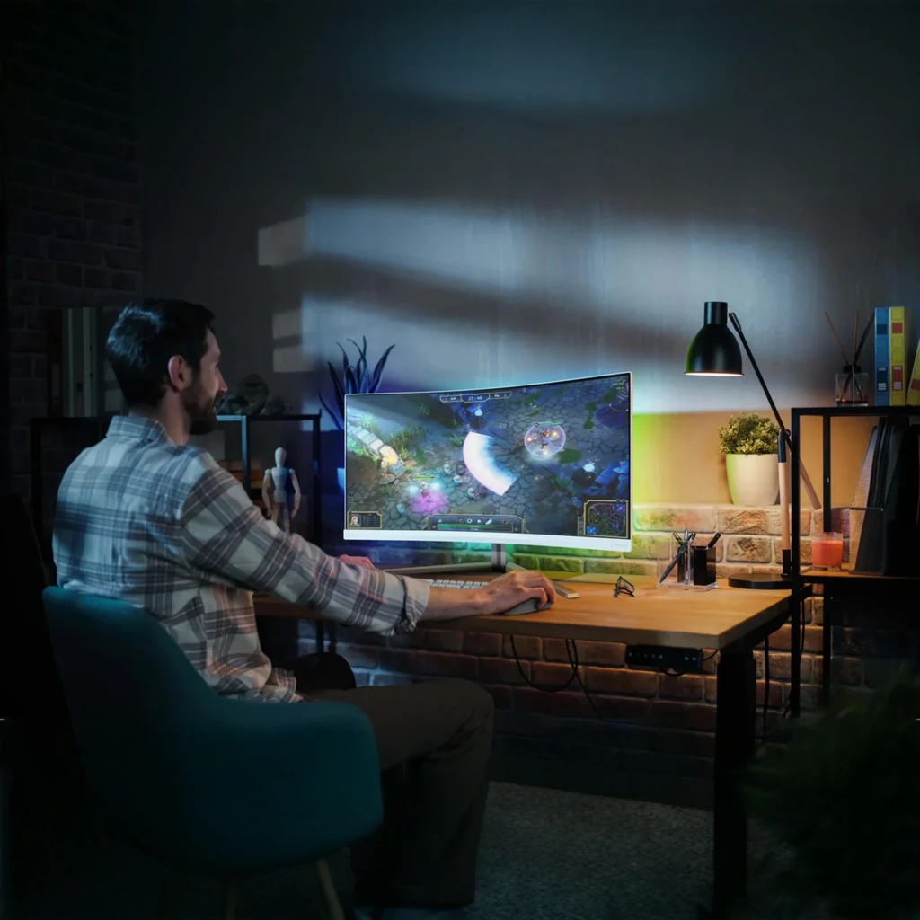 Philips Monitor Evnia 34M2C5501A 34 blanco, vista lateral: pantalla ultraancha curva en escritorio con usuario viendo