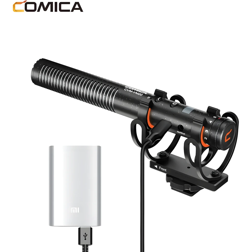 Micrófono Shotgun Comica CVM-VM20: cuerpo metálico negro con ranuras, suspensión antivibración, controles laterales y cable; incluye adaptador USB blanco