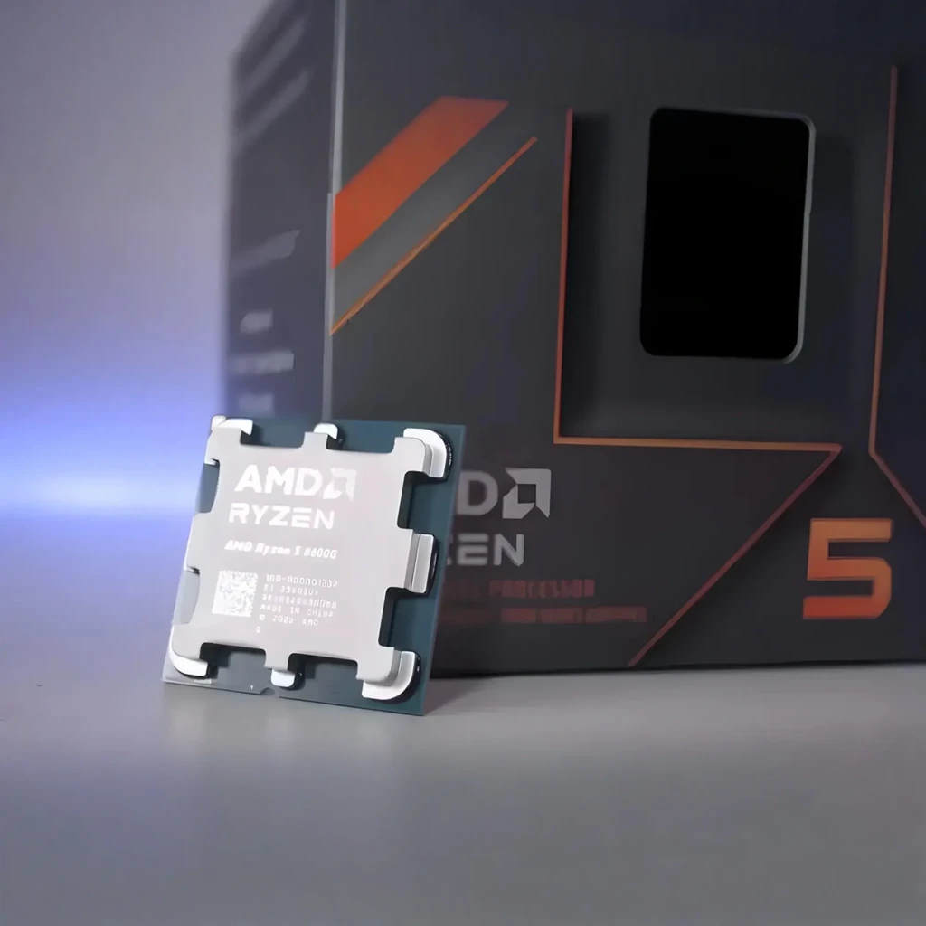 AMD Ryzen 5 8600G, vista frontal: procesador apoyado ante su caja oficial gris y naranja, IHS metálico con logo AMD Ryzen