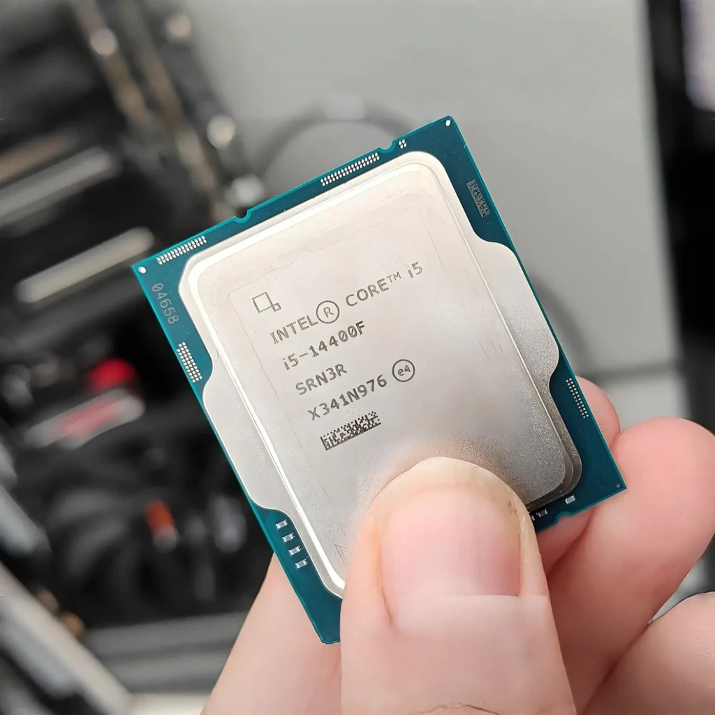 Intel Core i5-14400F, vista superior: mano sosteniendo el procesador, IHS plateado con grabado del modelo visible