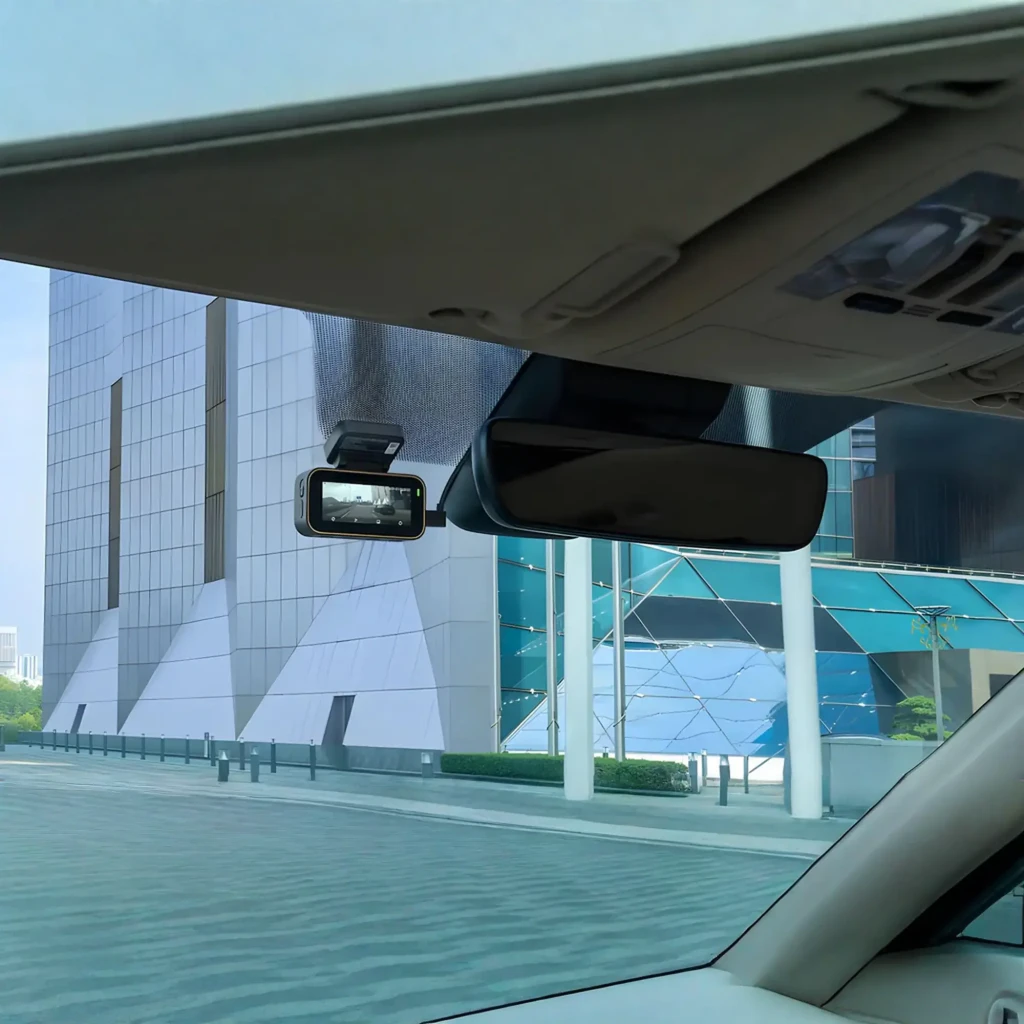 Dashcam 70mai A810 Lite 4K GPS WiFi instalada junto al retrovisor, pantalla a color mostrando la carretera, diseño compacto en negro, soporte adhesivo discreto