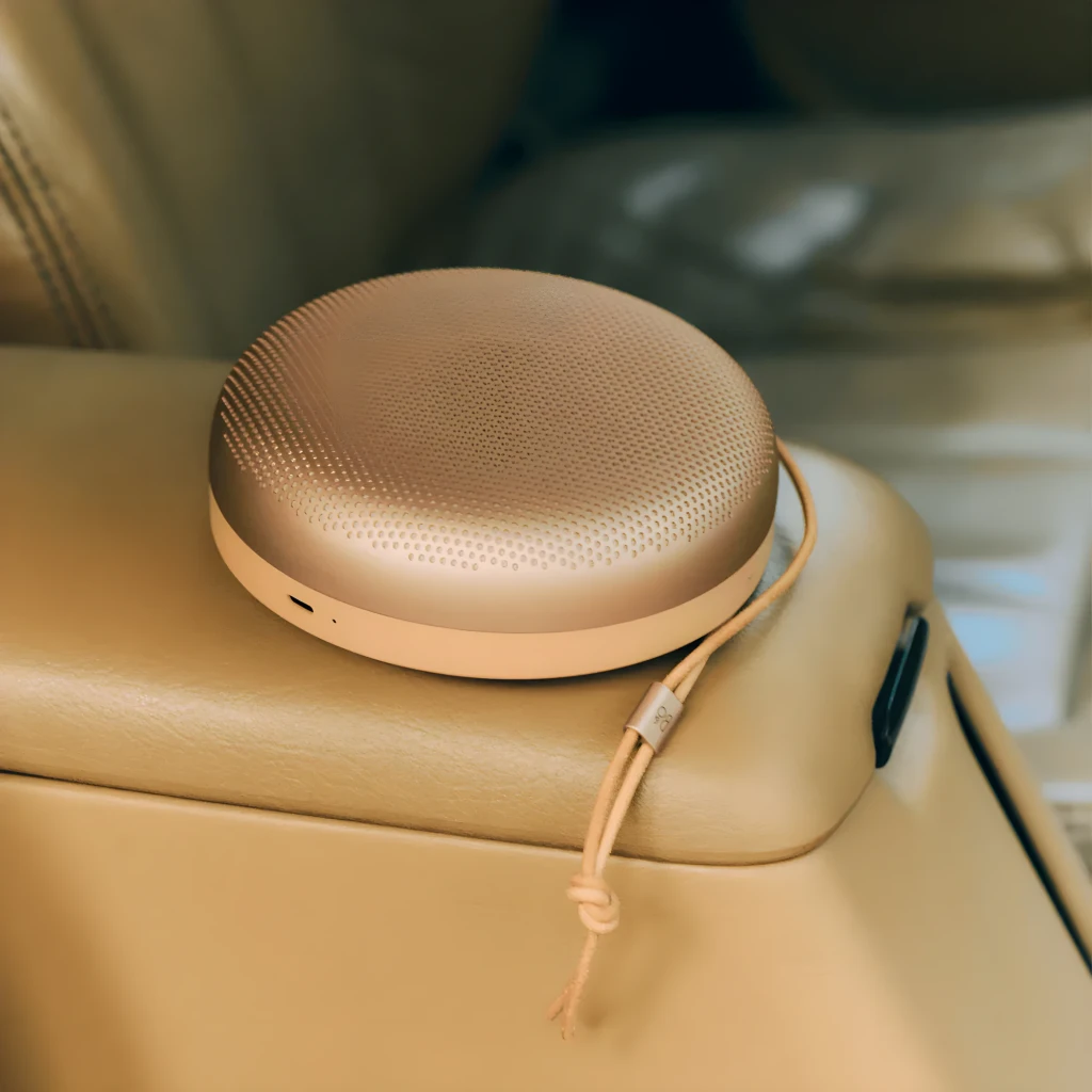 Bang & Olufsen Beosound A1 3rd Gen Honey Tone, vista lifestyle: altavoz sobre reposabrazos de cuero beige en interior de