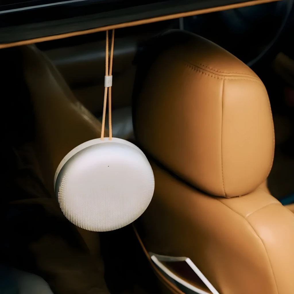 Bang & Olufsen Beosound A1 3rd Gen Honey Tone, vista lifestyle: colgado con correa en interior de coche con asiento de cuero