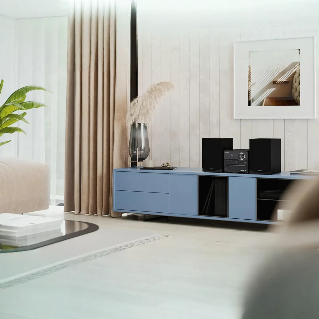 Sharp Microcadena XL-B512 45W negro, vista en salón: unidad central y altavoces sobre mueble TV azul en ambiente moderno