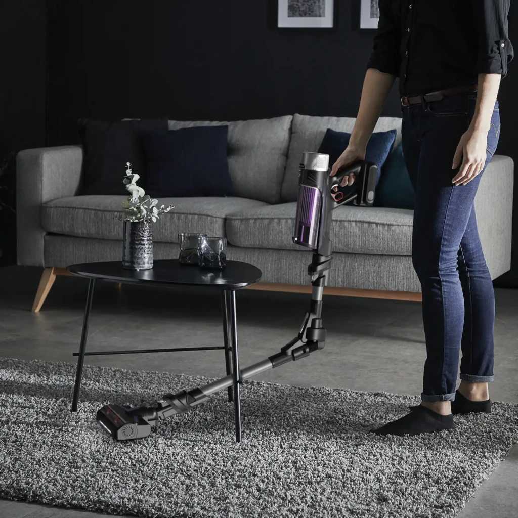 Rowenta X-Force Flex 9.60 Allergy RH2037WO Negro Púrpura, uso: persona aspirando alfombra en salón con tubo flexible doblado