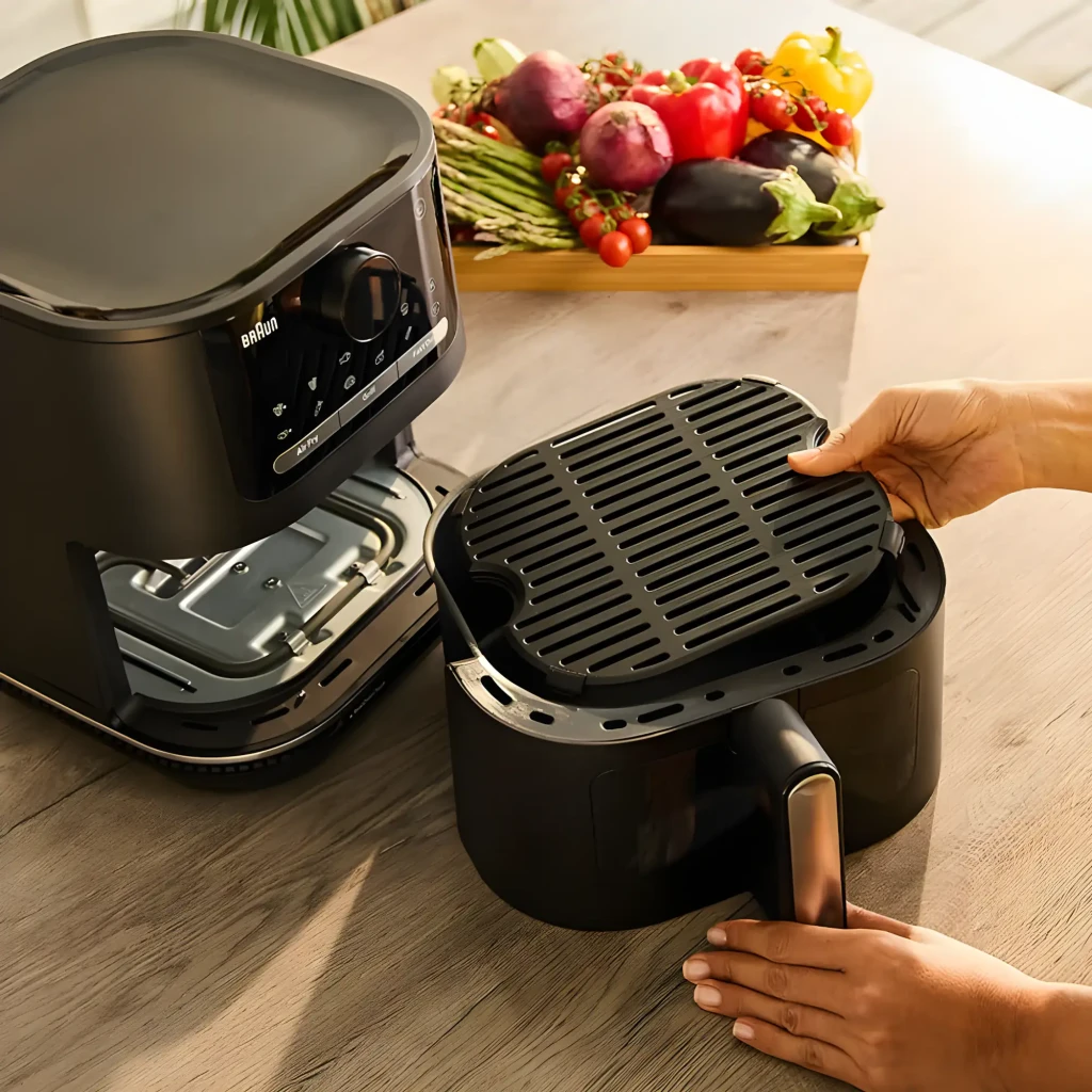 Braun Multifry 5 HF5075IBK Noir Gris, détail: mains retirant le panier avec grille, intérieur et panneau tactile visibles,