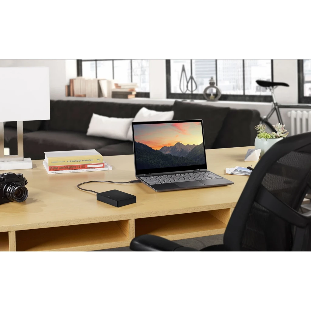 Seagate Expansion STKN1000400 1TB negro, vista lifestyle: disco conectado por USB a portátil sobre escritorio de madera