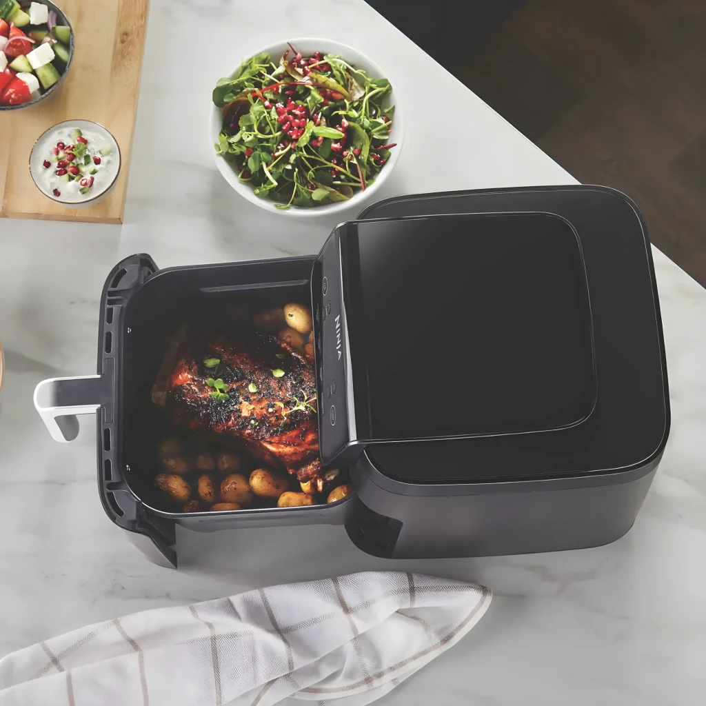 Ninja Freidora de Aire AF170EU 6.2L Negro, vista cenital: cesta abierta con pollo asado y patatas en encimera de mármol