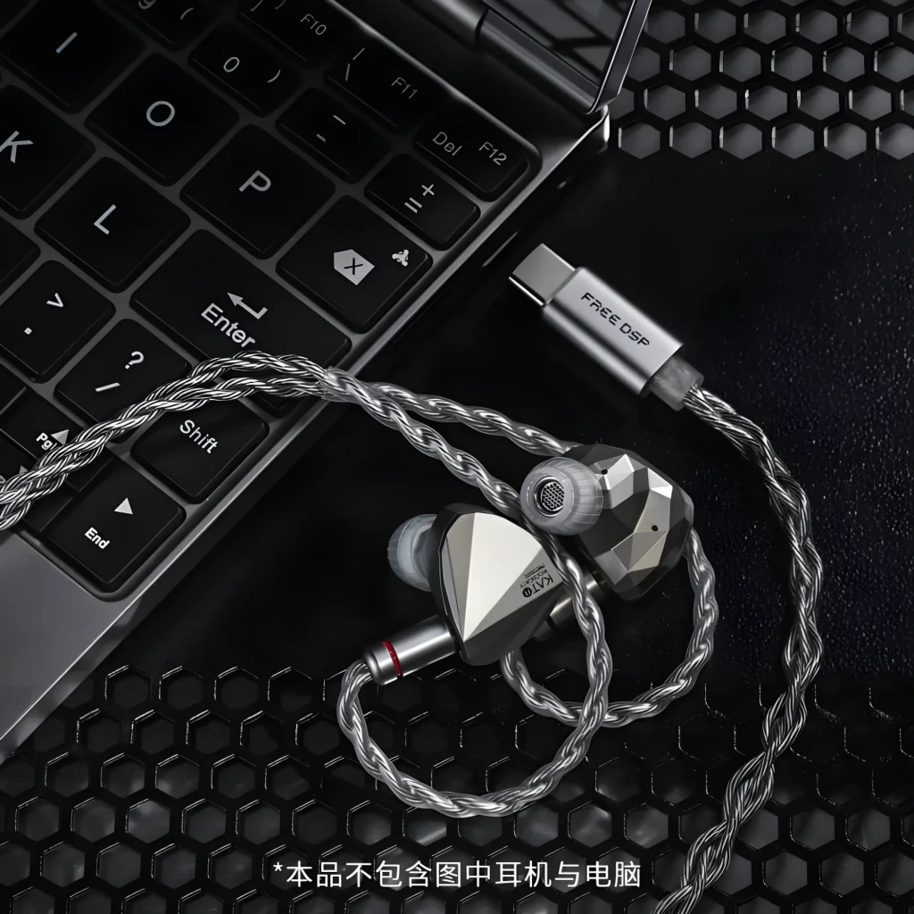 Cable Moondrop Free DSP USB-C con DAC/AMP y salida balanceada, trenzado plateado, conector USB-C metálico y acabado premium junto a laptop y malla hexagonal