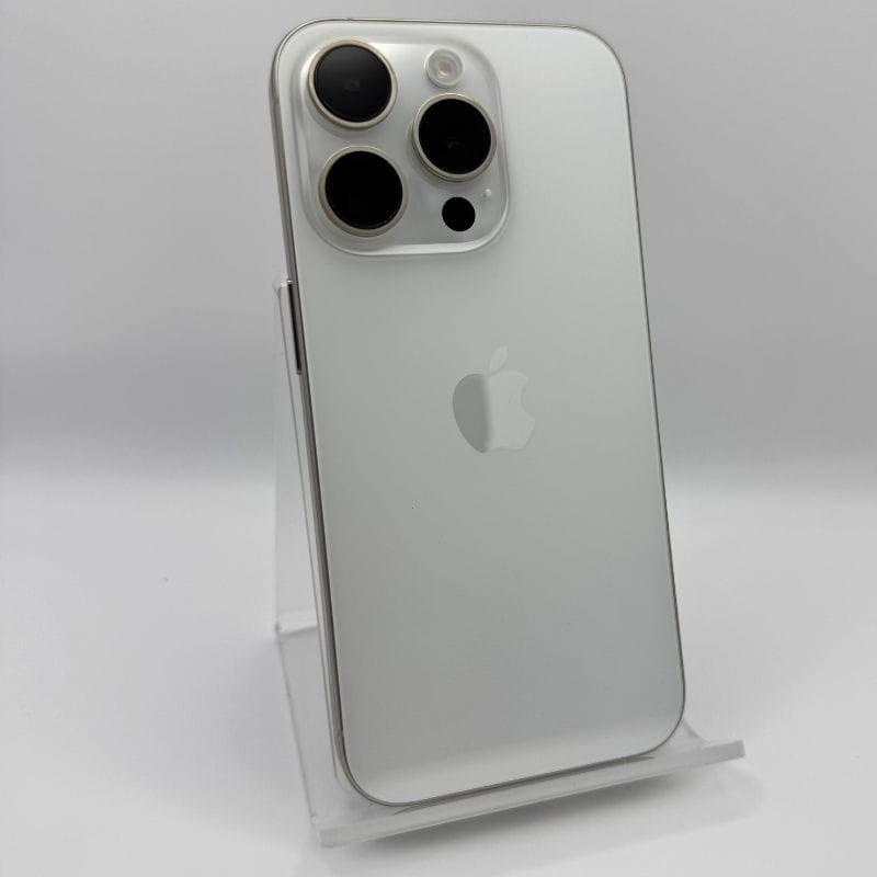 iPhone 15 Pro 5G 256GB en titanio blanco, renovado estado excelente. Trasera mate blanca, triple cámara grande, bordes metálicos pulidos en soporte.