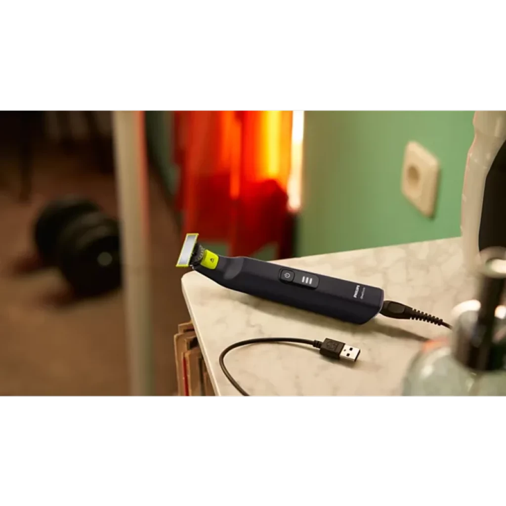 Philips OneBlade Pro 360 QP6542/15 visage et corps, manche bleu, lame 360 verte, bouton central, charge USB, posé sur un plan de salle de bain