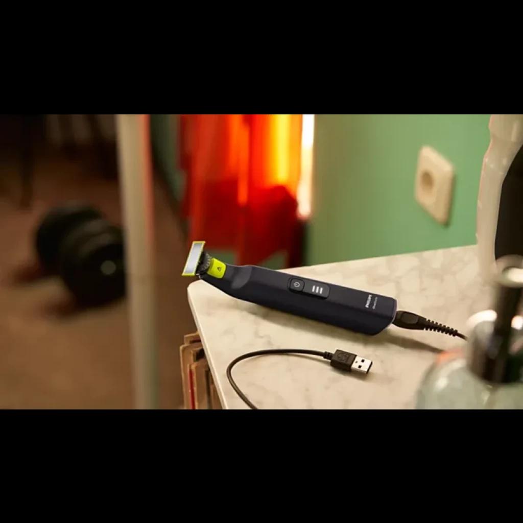 Philips OneBlade Pro 360 QP6542/15 visage et corps, manche bleu, lame 360 verte, bouton central, charge USB, posé sur un plan de salle de bain