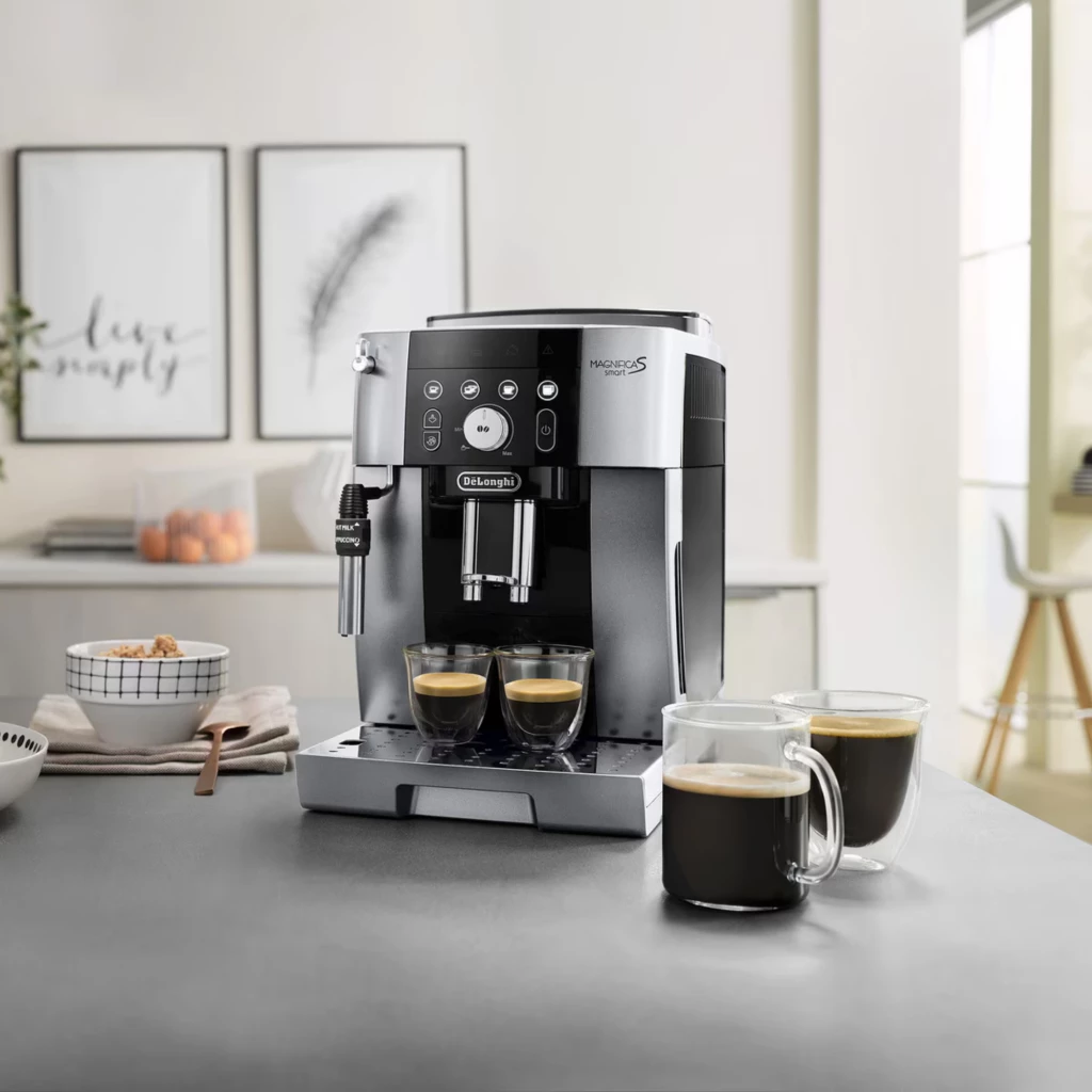 Cafetera superautomática plateada con panel frontal de botones, molinillo integrado, vaporizador lateral, doble salida de café y bandeja recoge gotas en acero