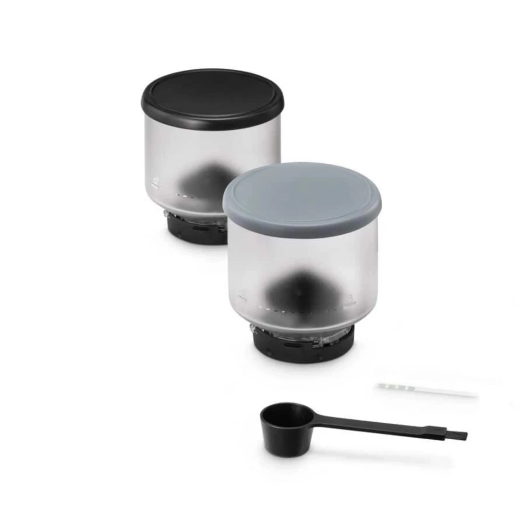 Dois recipientes Bean Switch translúcidos com tampas preta e cinza, indicadores na base e colher dosadora preta, compatíveis com DeLonghi Rivelia