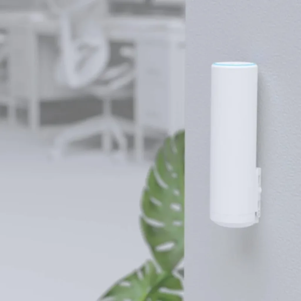 Ubiquiti U6 Mesh cilíndrico blanco montado en pared, LED azul en la parte superior, diseño minimalista, puerto lateral cubierto, ideal para interiores PoE