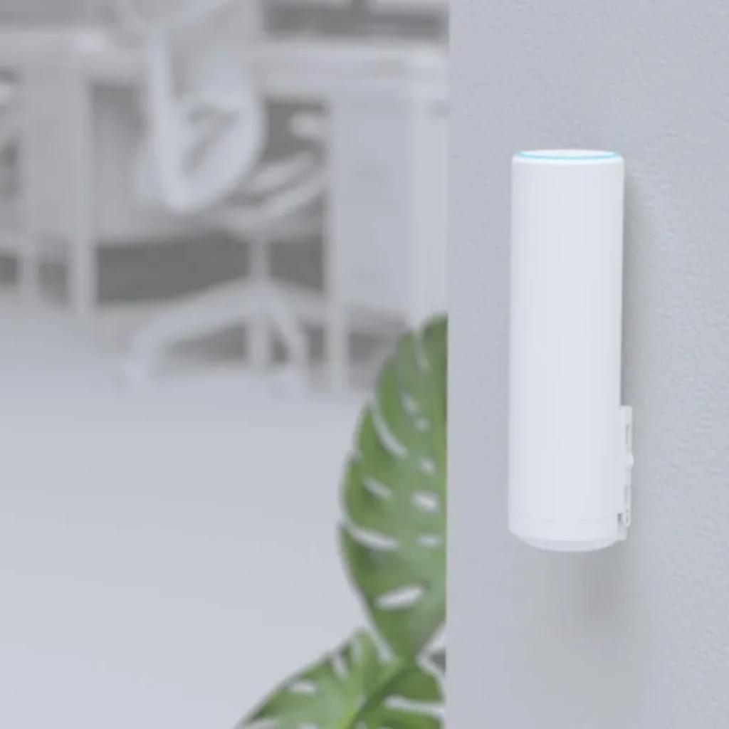 Ubiquiti U6 Mesh cilíndrico blanco montado en pared, LED azul en la parte superior, diseño minimalista, puerto lateral cubierto, ideal para interiores PoE