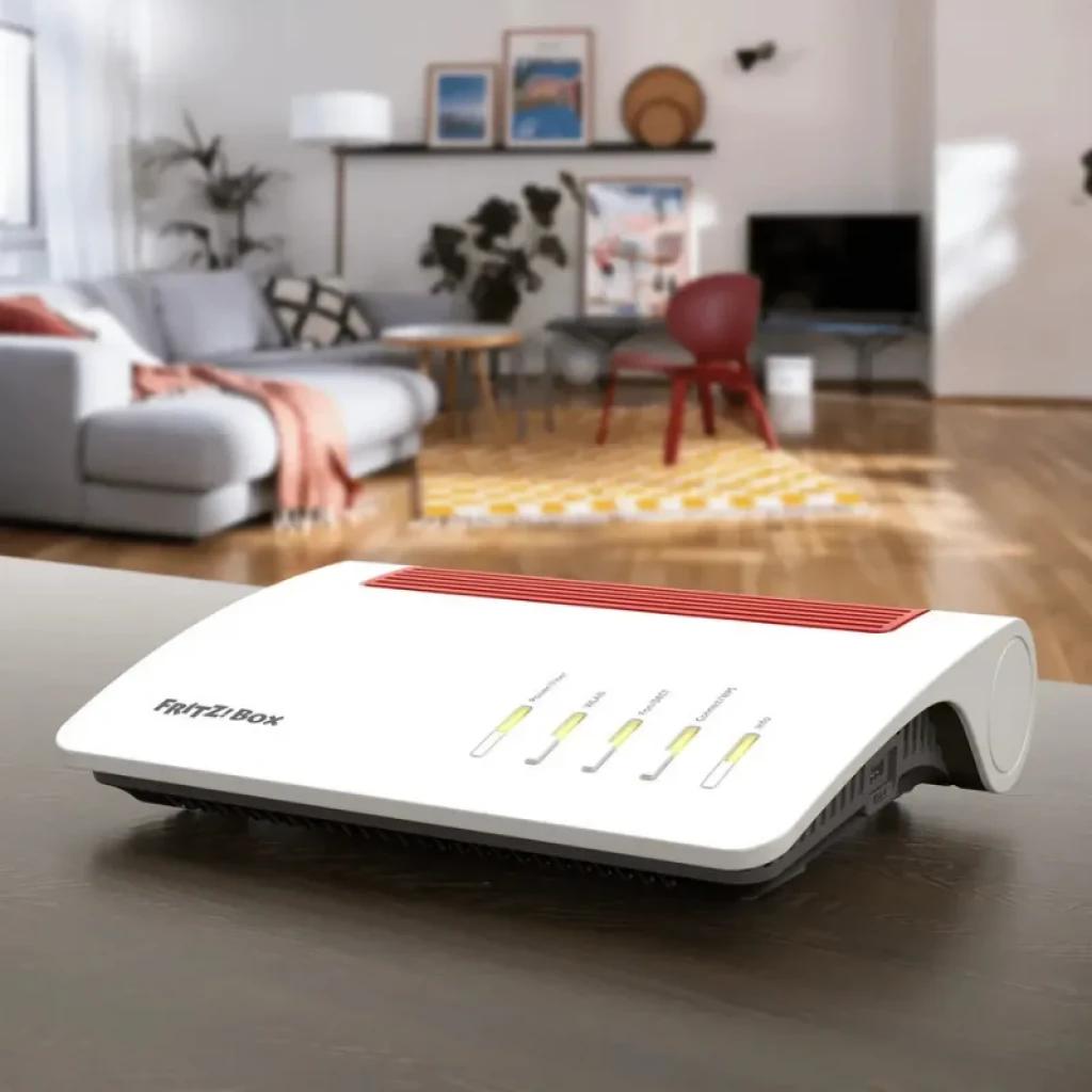 Router FRITZ!Box 5590 Fiber WiFi 6 en color blanco con rejilla roja, LEDs de estado frontales y diseño curvo, colocado sobre mesa en sala moderna