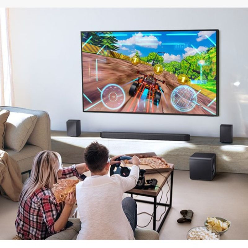 Samsung HW-QS700F Subwoofer Dolby Atmos, image réelle d'une famille jouant à la télévision connectée à la barre de son.