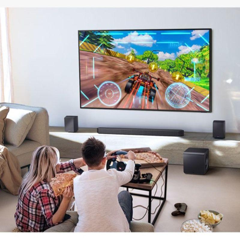 Samsung HW-QS700F Subwoofer Dolby Atmos, image réelle d'une famille jouant à la télévision connectée à la barre de son.