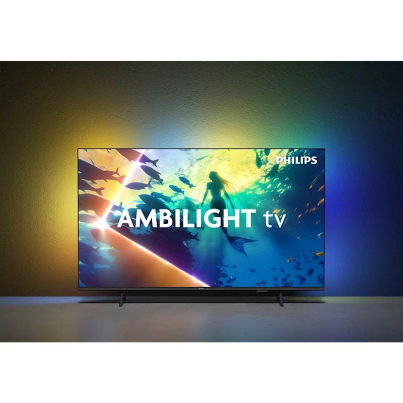 Philips 50PUS8010 50" 4K UHD, cadre noir fin, pied discret. Ambilight multicolore arrière diffusant une lueur immersive sur le mur.