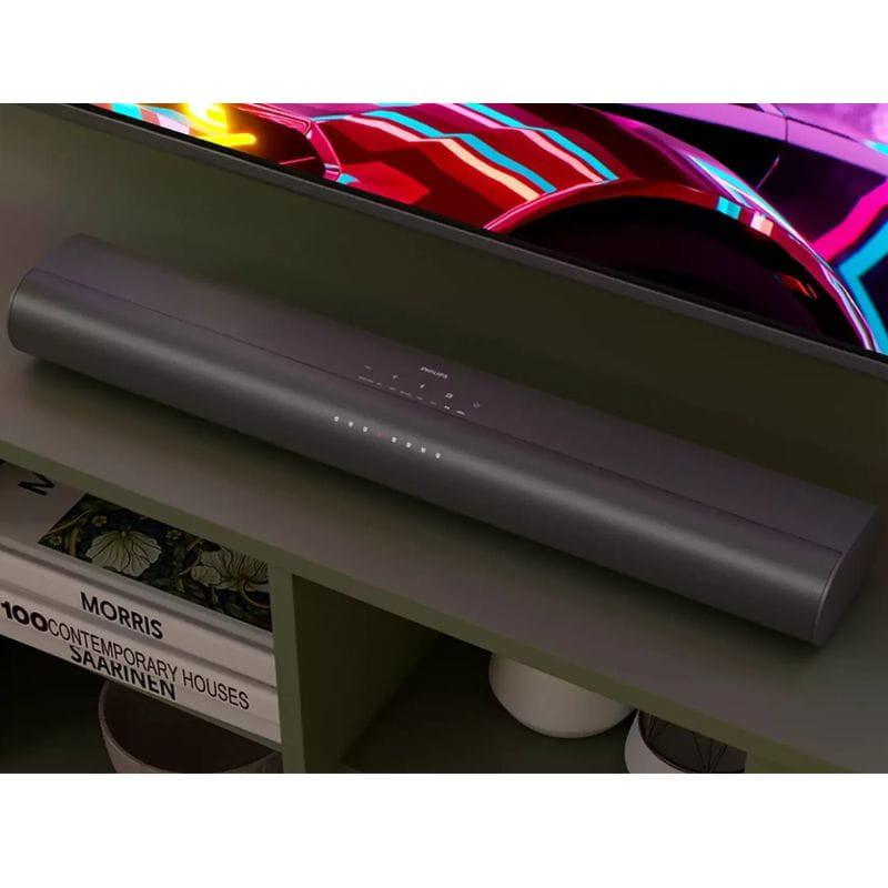 Barre de son grise compacte avec LED d’état sur le dessus, design épuré sous TV, finitions mates, compatible avec subwoofer pour setup 2.1 80 W