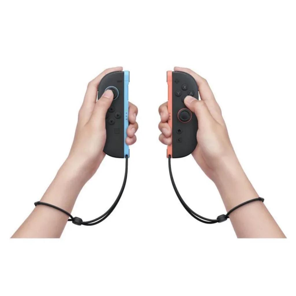 Joy-Con azul y rojo con correas de muñeca, sostenidos en manos, botones y sticks visibles para Nintendo Switch 2 + Mario Kart World + Street Fighter 6