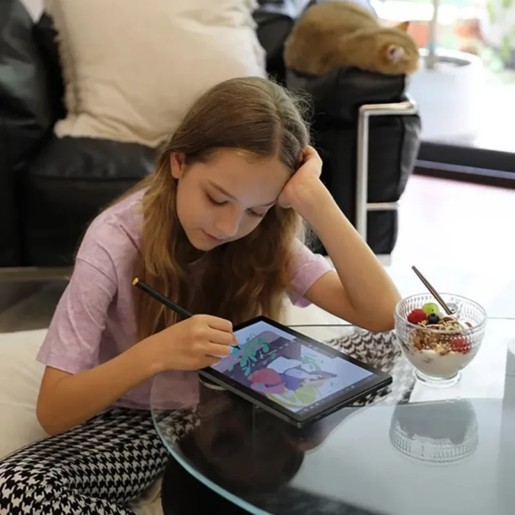 Tableta gráfica Huion Slate 10 de 10,1 pulgadas con pantalla laminada FHD+, lápiz activo dibujando en colores vivos sobre superficie negra en mesa de cristal