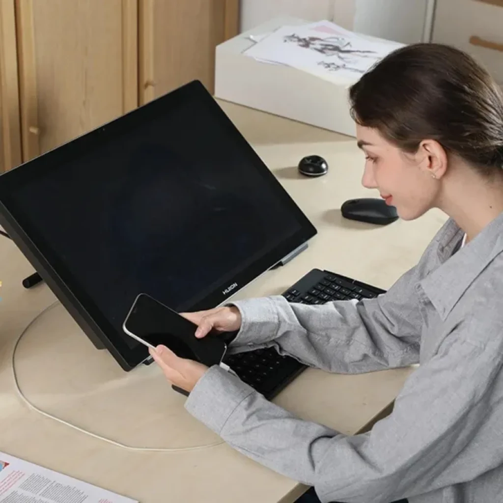Huion Kamvas Studio 24 KS2401 en escritorio con pantalla táctil inclinada, biseles negros, soporte trasero y stylus junto a teclado y ratón