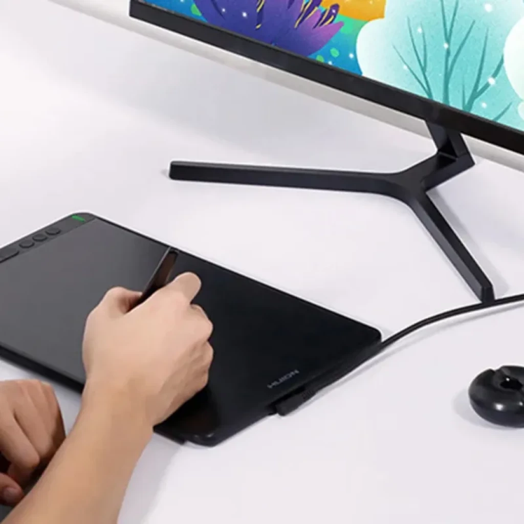 Tableta Huion Kamvas 12 GS1161 de 11,6 pulgadas negra con lápiz óptico, botones laterales, conexión por cable y superficie de dibujo mate junto a monitor