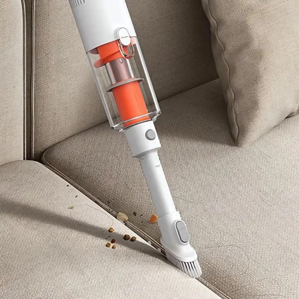 Xiaomi Vacuum Cleaner P30 limpiando sofá con boquilla delgada y cepillo integrado; cuerpo blanco con depósito transparente y filtro naranja, succionando