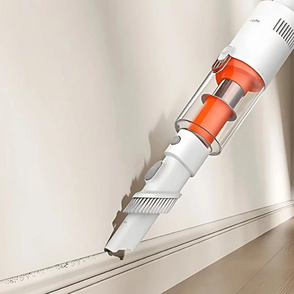 Xiaomi Vacuum Cleaner P30 con boquilla estrecha y cepillo angular, cuerpo blanco y acentos naranjas, limpiando bordes y rincones junto al zócalo de una pared