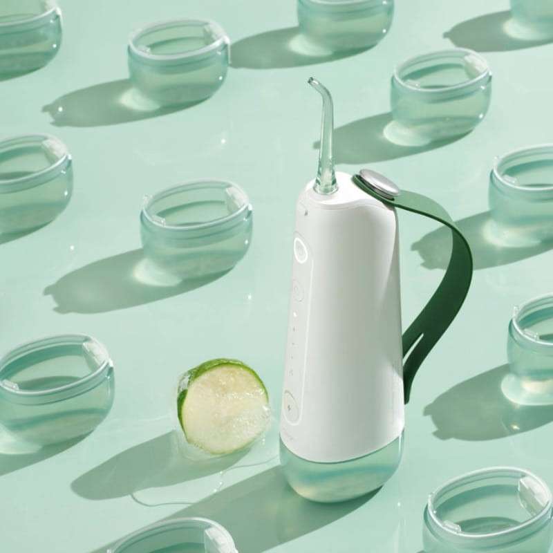 Oclean W10 Vert irrigateur dentaire portable blanc et vert avec embout fin, base transparente et sangle latérale, design moderne sur fond vert menthe