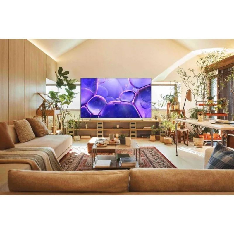 Samsung TU65U8005FU 65" 4K UHD LED Smart TV con marco fino, pantalla grande y colores vivos; destaca en salón moderno con plantas y luz natural.