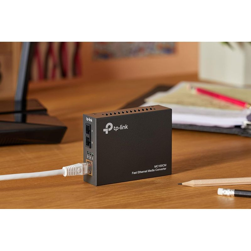 TP-Link MC100CM conversor multimodo 10/100 Mbps em caixa preta compacta, com portas RJ45 e fibra, LED de status e ventilação superior; cabo Ethernet conectado