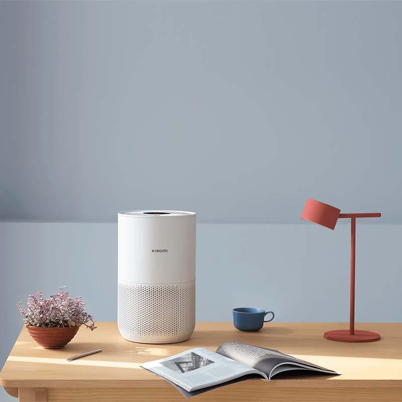 Purificateur dAir Xiaomi Smart Air Purifier 4 Compact blanc, format cylindrique, corps perforé, sommet noir avec grille, posé sur un bureau minimaliste
